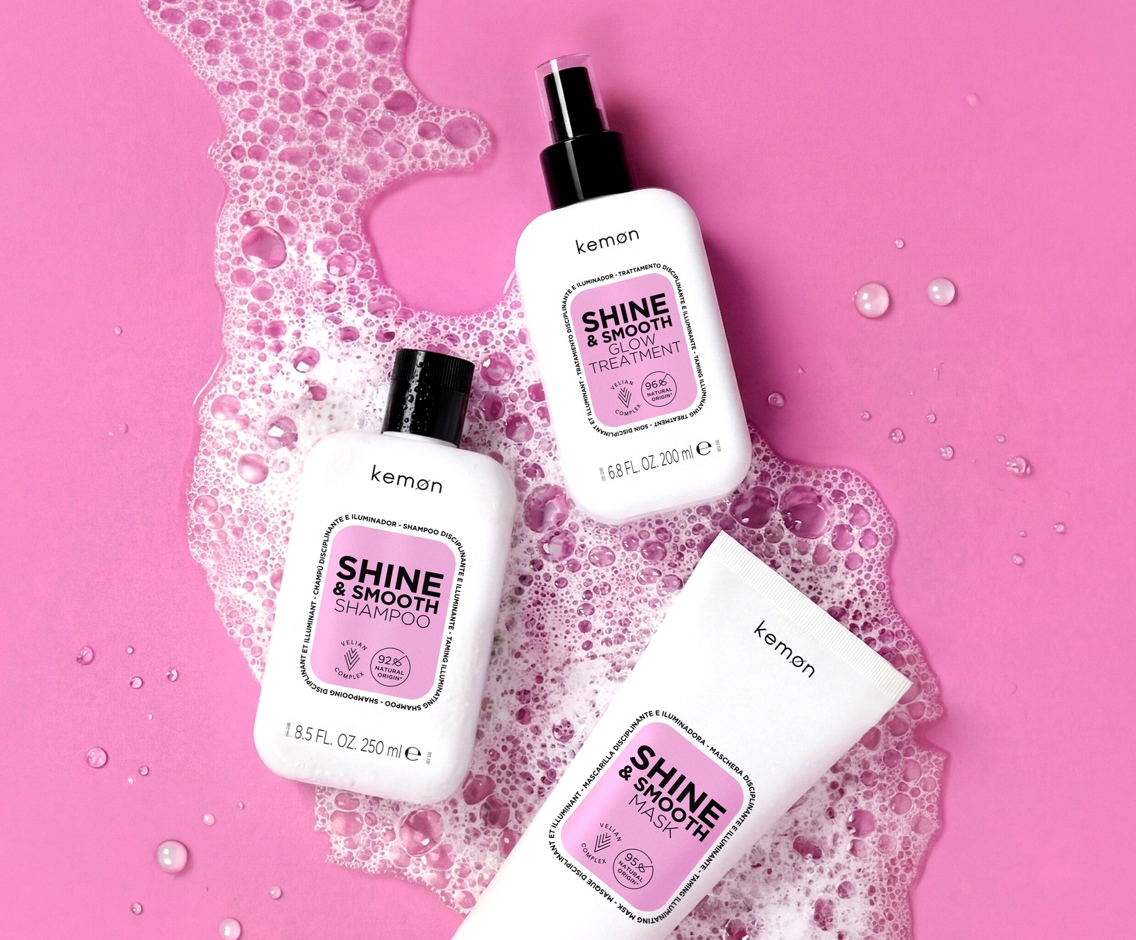 Produkty Kemon Shine & Smooth do pielęgnacji włosów – szampon, maska i spray nawilżający na różowym tle z pianką.